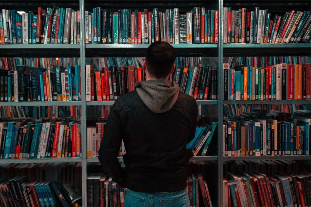 BAM! Be A Man. Man Look At Books On A Shelf.